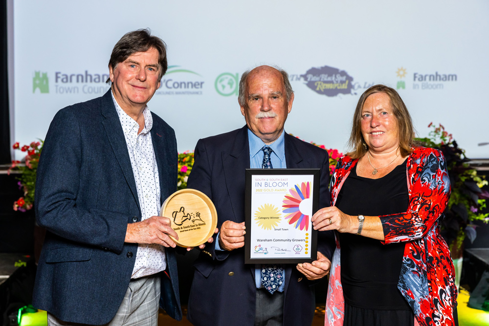 title of best small town, an award collected by Wareham Community Growers chairman Rod Curtis, left, and treasurer Sue Dean, right, from Mayor of Farnham Alan Earwaker. PHOTOS: Wareham Community Growers