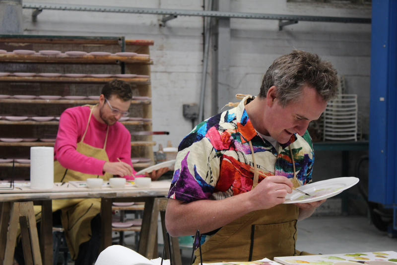 Dan painting a flower on his plate. 