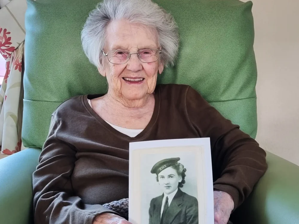Elizabeth House resident Kathleen with a photo of herself aged 18 in her Wren uniform